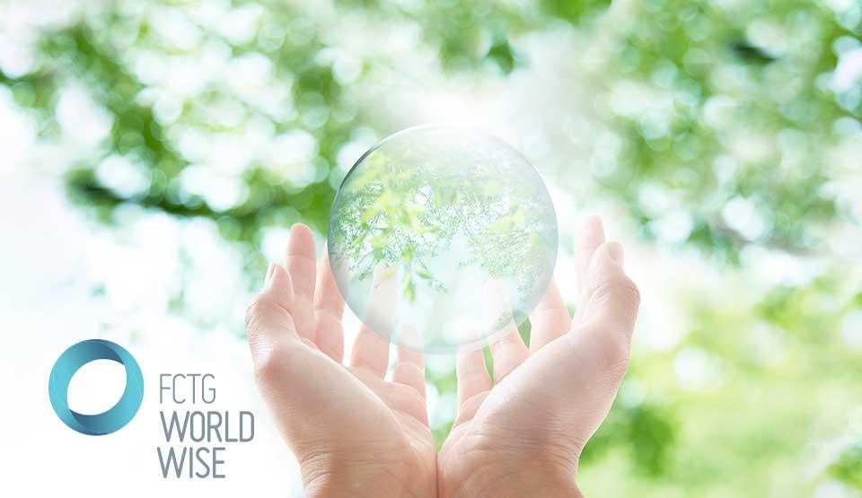 FCTG World Wise Hands holding a glass orb with trees in the background